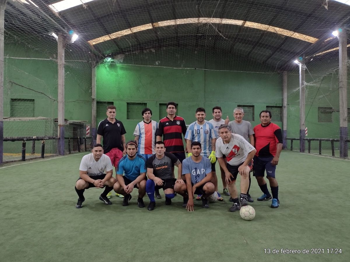 Equipo de amigos posando en la cancha de fútbol